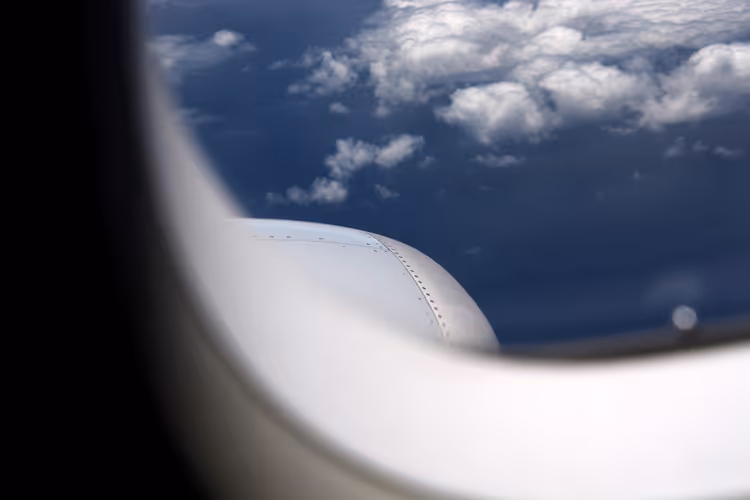 Utsikt fra flyvinduet av vinge og skyer