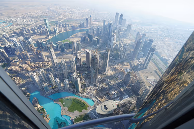 Wolkenkratzer von Downtown Dubai und türkisfarbene Lagunen von oben, durch das Fenster einer Aussichtsplattform gesehen