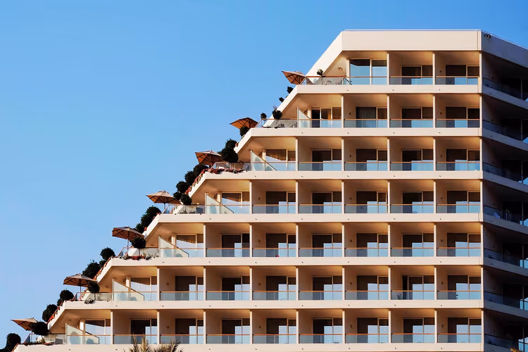 Hotellfasade med terrasserte balkonger og parasoller