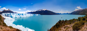 Perito-Moreno-Gletscher an einem türkisfarbenen See, schneebedeckte Berge und grüne Hänge unter blauem Himmel