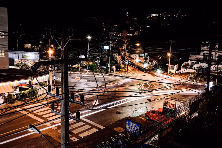 Nächtliche Straßenkreuzung mit Autolichtern und Kabeln