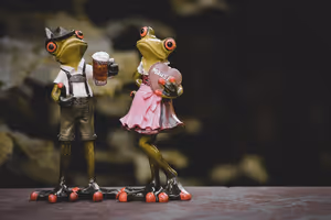 Zwei Froschfiguren in bayerischer Tracht, eine in Lederhose mit Bierkrug, die andere im rosa Dirndl mit Herz