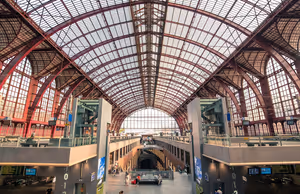 Gewölbtes Dach aus Eisen und Glas über der mehrstöckigen Bahnhofshalle von Antwerpen-Centraal, unten Reisende