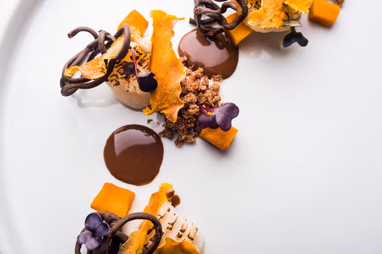 Gourmetdessert med sjokolade og gresskar på en hvit tallerken