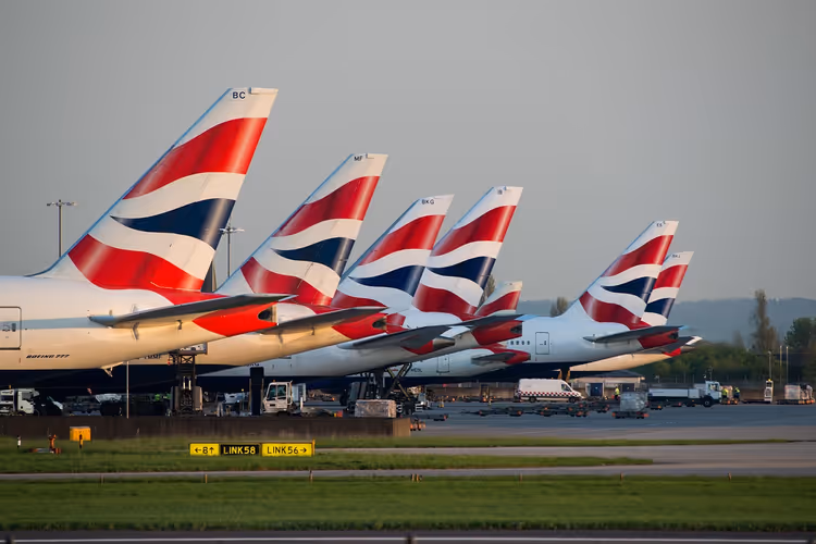 Reihe von Flugzeugleitwerken in Rot, Weiß und Blau am Flughafen Heathrow im warmen Abendlicht