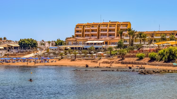 Groot geel hotel aan de zeekant met strand