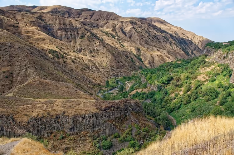Garni-Schlucht in Armenien mit Felswänden aus Basaltsäulen, grünem Talboden und trockenen braunen Berghängen