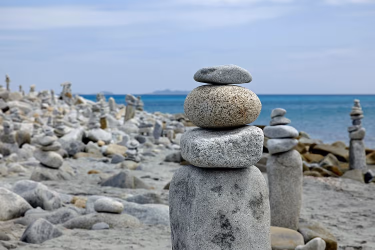 spiaggia rocciosa con omini di pietra in riva al mare
