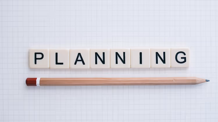 Слово PLANNING из плиток и карандаш на клетчатой бумаге
