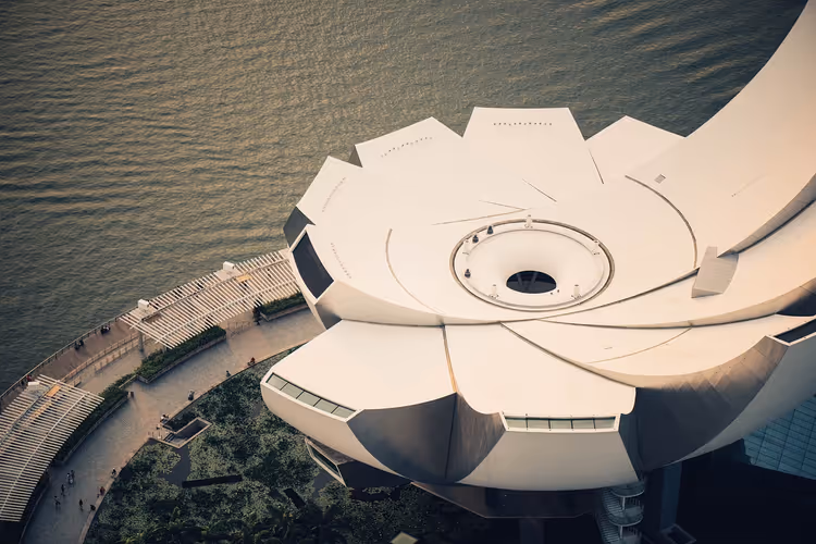 Weißes Dach des ArtScience Museum in Singapur in Form einer Lotusblüte, von oben gesehen neben der Uferpromenade