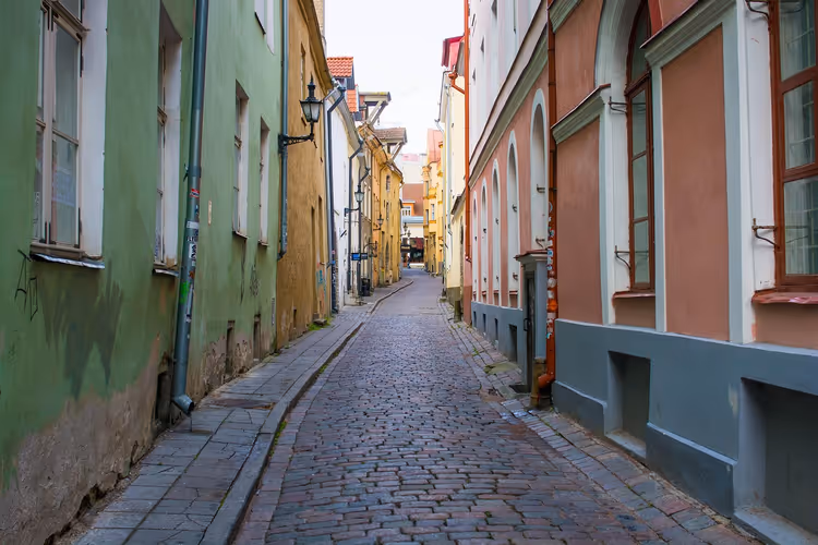 Schmale Kopfsteinpflastergasse in der Altstadt von Tallinn, gesäumt von grünen, gelben und rosa historischen Häusern