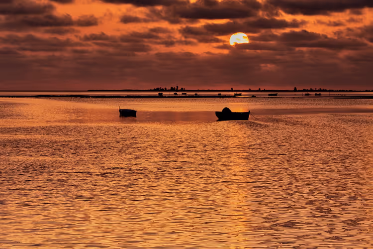 Zonsondergang boven zee met boten vlak bij de kust