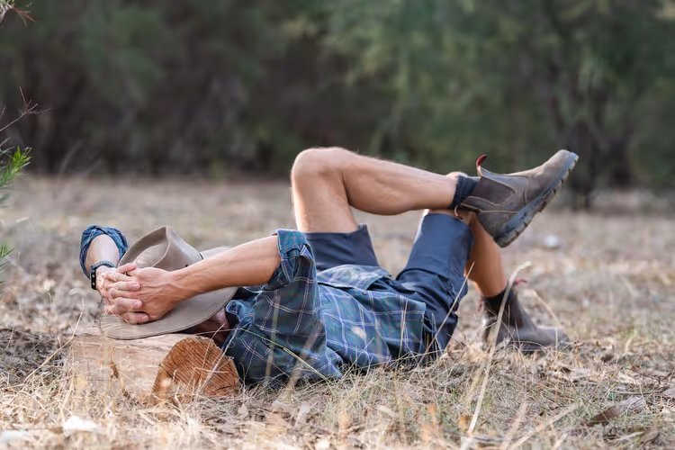 Homem a descansar deitado na erva num campo