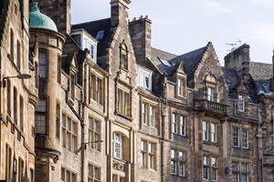 Sandsteinfassaden von Mietshäusern mit Treppengiebeln, Dachgauben und grüner Kupferkuppel in der Altstadt von Edinburgh