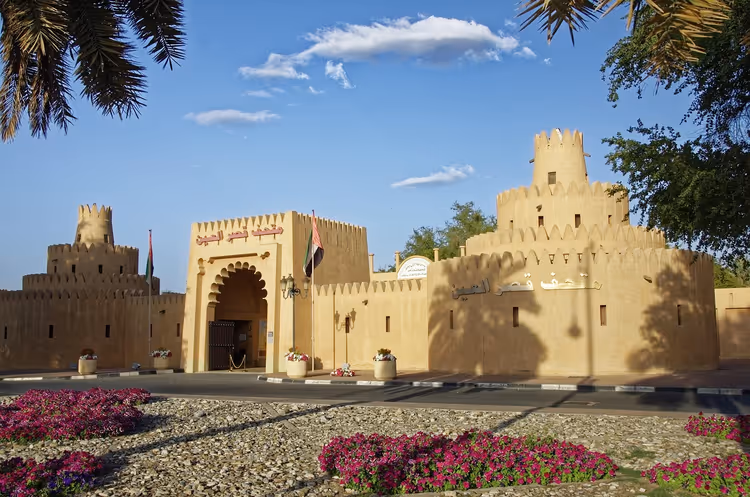 Al Ain fortmuseum med palmer og blomsterbed
