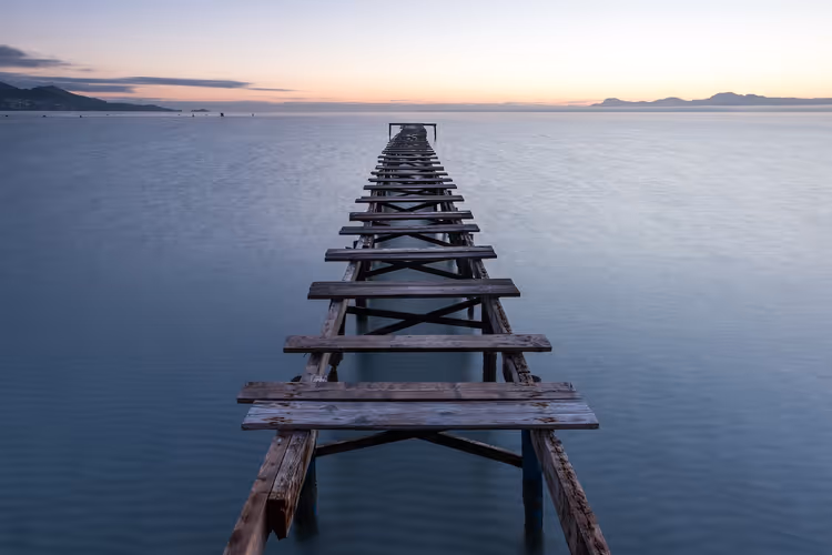 Houten pier in zee bij zonsondergang voor de kust van Alcudia