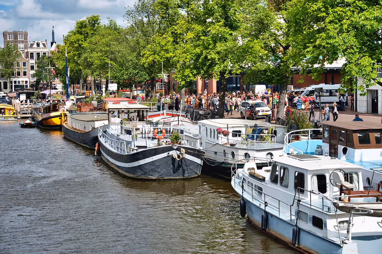 Hausboote und Boote entlang einer Gracht in Amsterdam