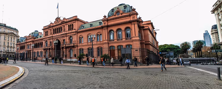 Rosafarbener Palast Casa Rosada in Buenos Aires, davor überqueren Fußgänger den gepflasterten Platz