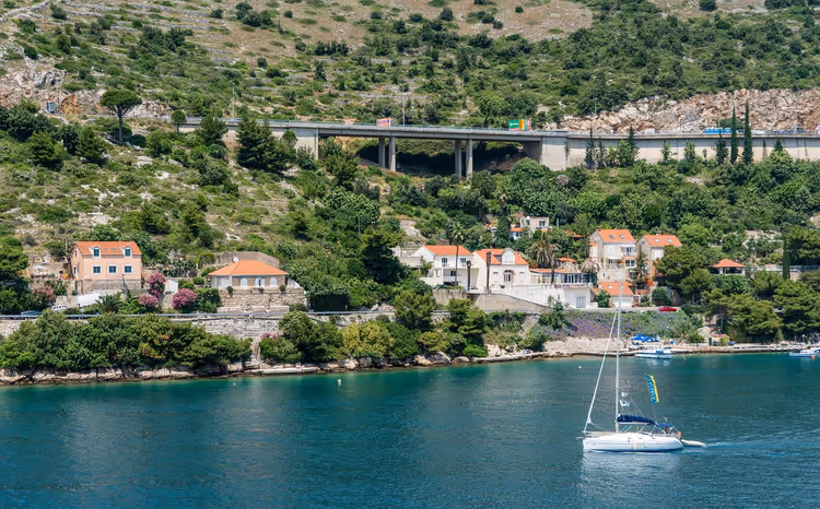 Kustzicht op Dubrovnik met een brug en een jacht