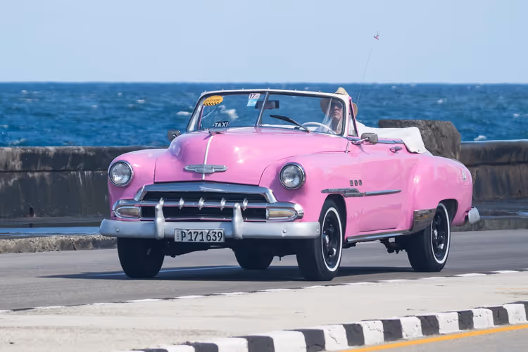 Havana sahilinde pembe retro üstü açık taksi