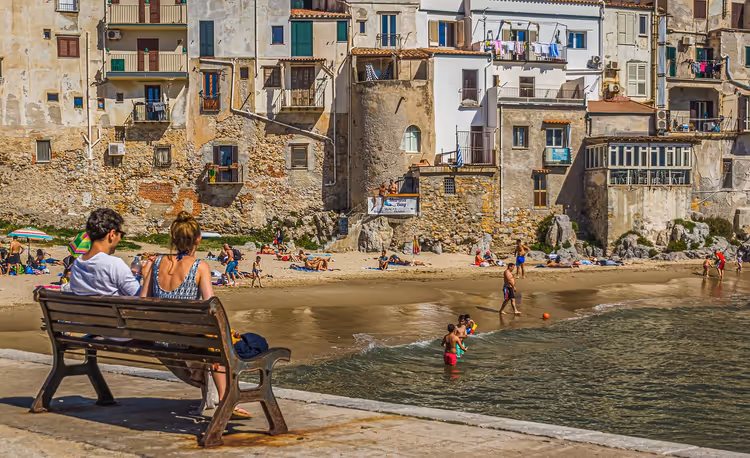 Strand van Cefalù met bezoekers tegen de achtergrond van de oude stad