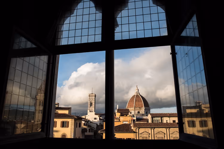 Kuppel des Doms von Florenz und Giottos Glockenturm, durch ein dunkles Bleiglasfenster unter sonnenbeschienenen Wolken gesehen