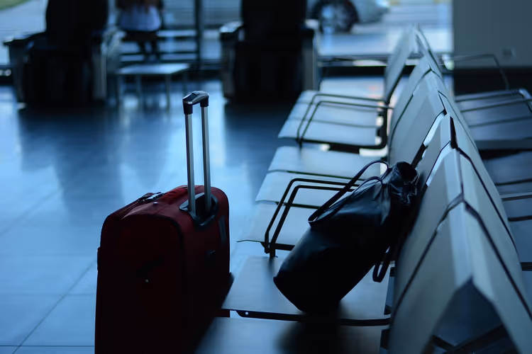 rode koffer met uitgeschoven handgreep op de luchthaven
