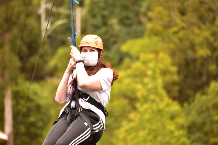 Vrouw aan een zipline met helm en masker
