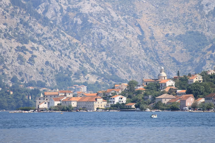 Kotor Körfezi kıyısında küçük bir kasaba ve dağların panoraması