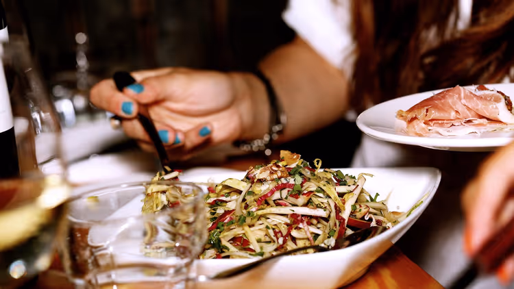 Bir restoranda öğle yemeği: salata, prosciutto ve şarap