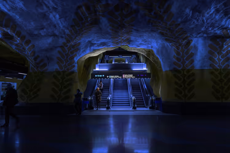 In den Fels gehauene U-Bahn-Station in Stockholm, die höhlenartige Decke blau bemalt mit Blattmotiven über den Rolltreppen