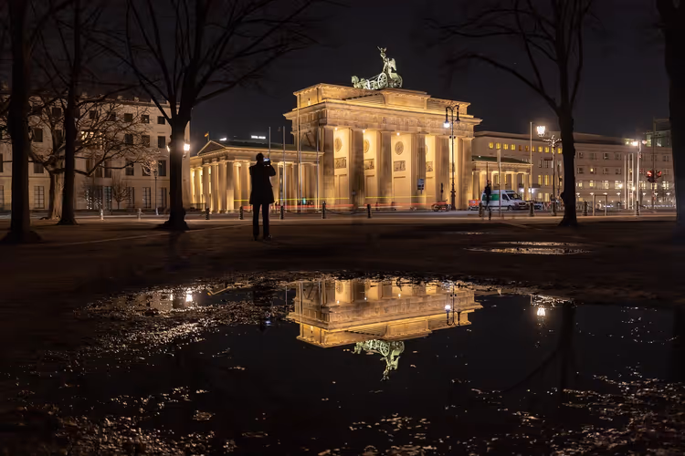 Brandenburger Tor bei Nacht mit Spiegelung in einer Pfütze