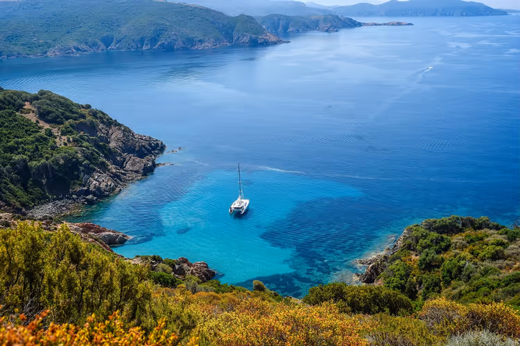 Türkisfarbene Lagune mit einer Yacht zwischen felsigen Ufern