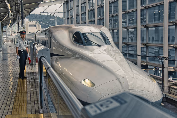 Shinkansen an einem Bahnhof mit einem Mitarbeiter am Bahnsteig