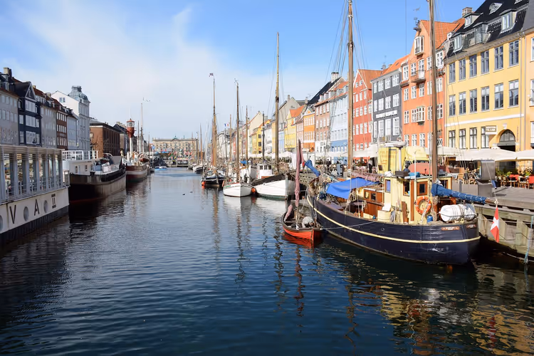 Hölzerne Segelboote an einem Kanal mit bunten Giebelhäusern in Dänemark an einem sonnigen Tag