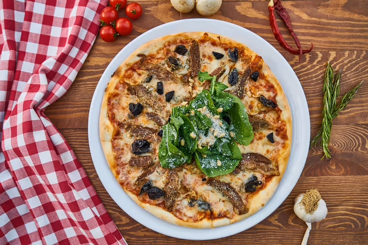 Pizza med sopp og spinat på et trebord
