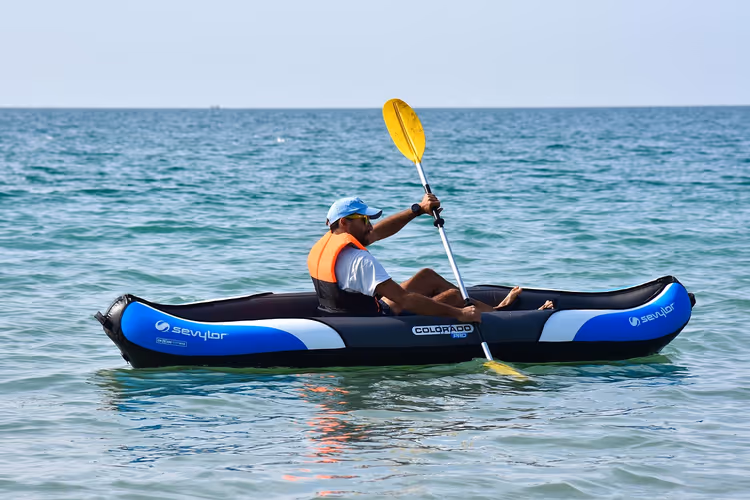 Man peddelend in een opblaasbare kajak op zee