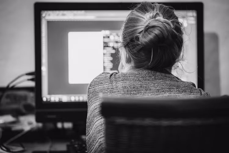 Persoon op de rug gezien achter een computer in een thuiswerkplek