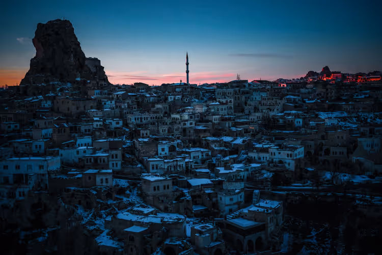 Winter evening in Cappadocia: town under snow and a rock formation