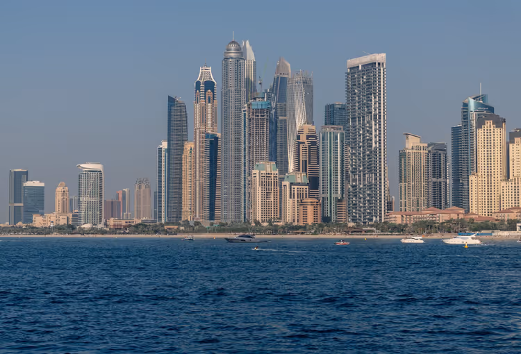 Gruppe von Hochhaustürmen an der Uferfront von Dubai vom Meer aus gesehen, davor vorbeifahrende Boote