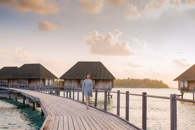 Overwater villa's met rieten dak bij zonsondergang