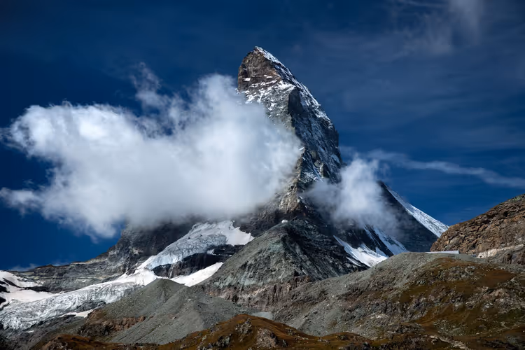 De Matterhorn in de wolken boven rotsachtige hellingen