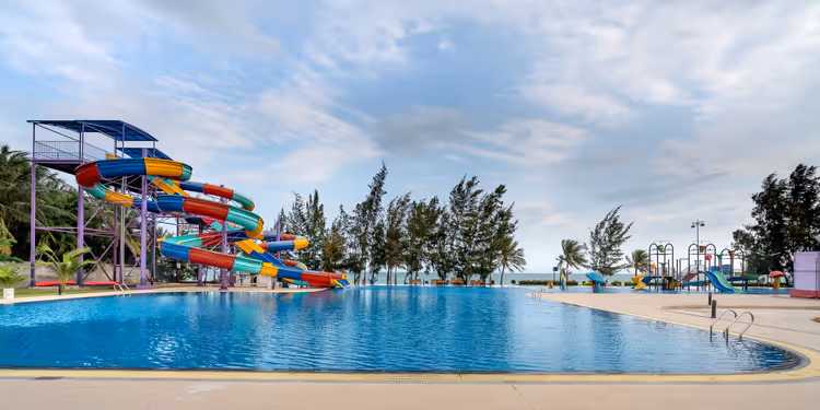 Kleurrijke glijbanen van een waterpark bij een zwembad met palmbomen