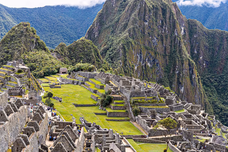 Steinruinen und grüne Terrassen von Machu Picchu in Peru unter steilen bewaldeten Berggipfeln