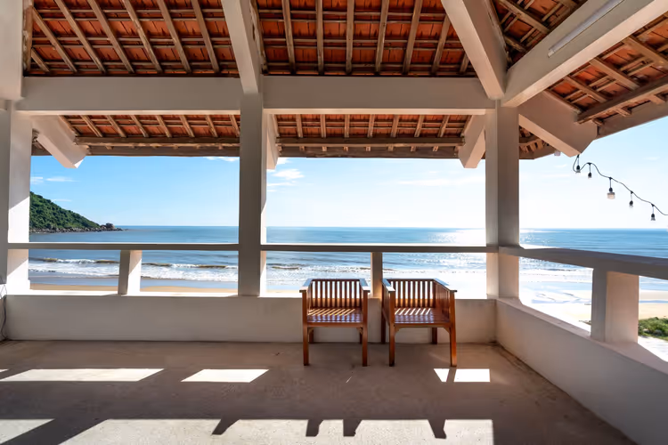 Holzstühle auf einer Terrasse mit Blick aufs Meer