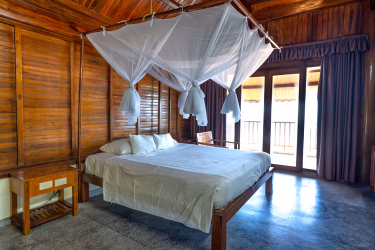 Zimmer mit Moskitonetz über dem Bett in einem Holzhaus