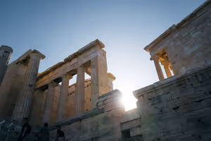 Marmorsäulen und Steinmauern des Eingangstors der Akropolis in Athen, von unten gesehen, mit der Sonne dahinter