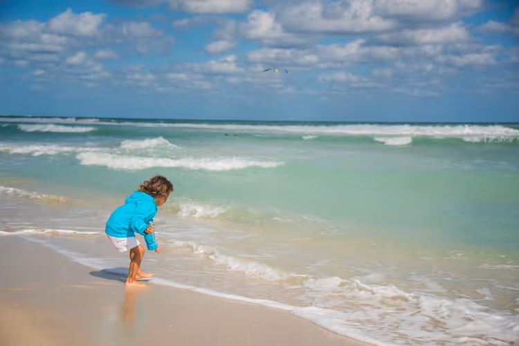 Kleinkind spielt am Wasser an einem Sandstrand