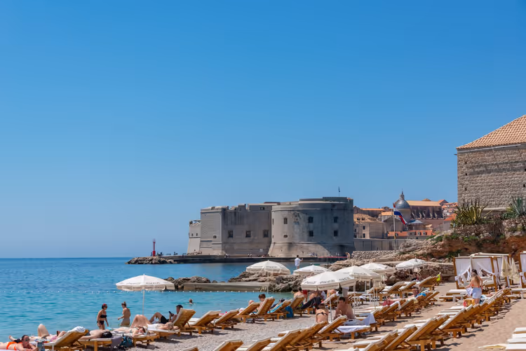 Strand med solsenger ved festningen i Dubrovnik
