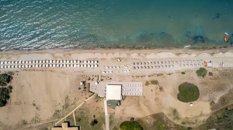 Luftfoto av stranden med parasoller og resortbygg
